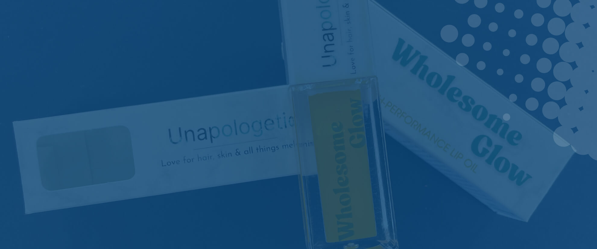 Bottle of Wholesome Glow lip oil with product packaging on a blue background