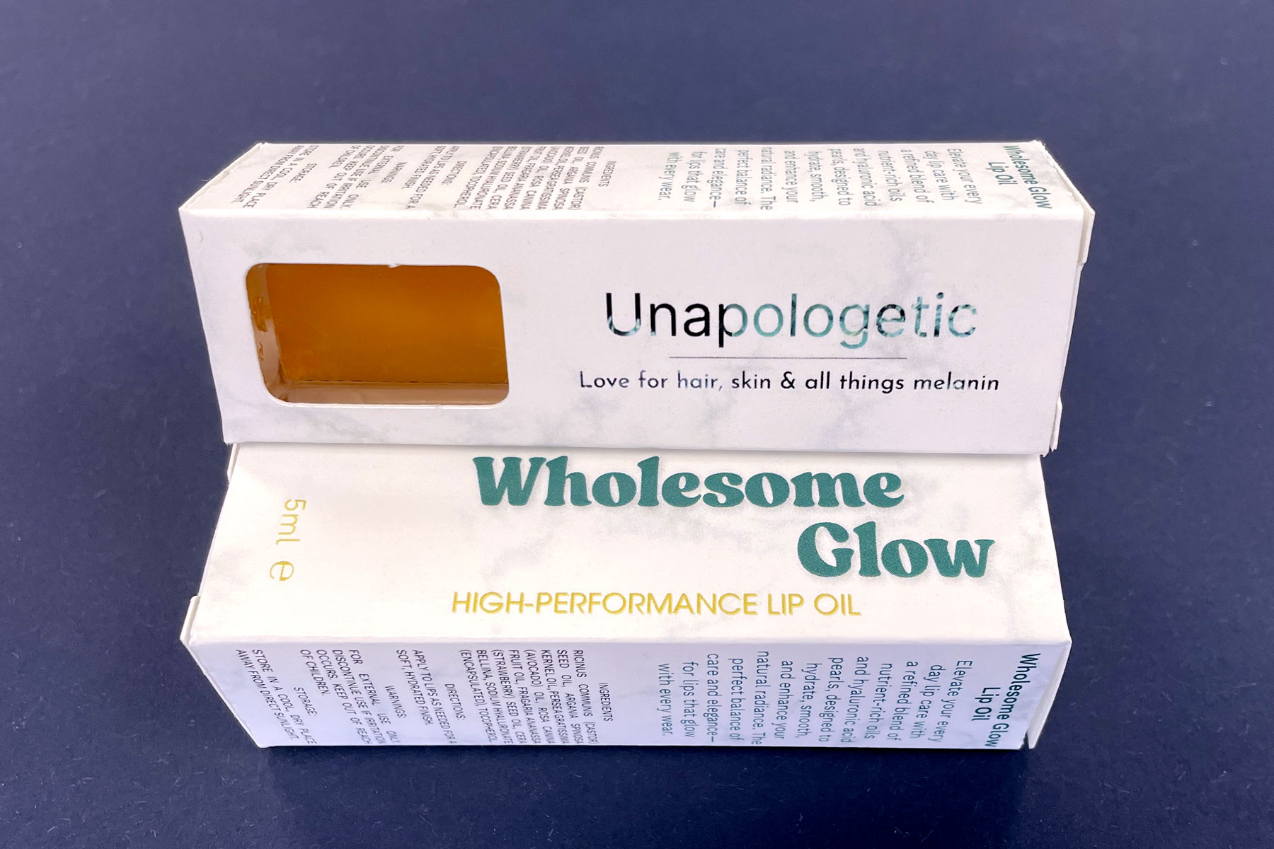 Wholesome Glow lip oil in a bespoke product carton on a blue background